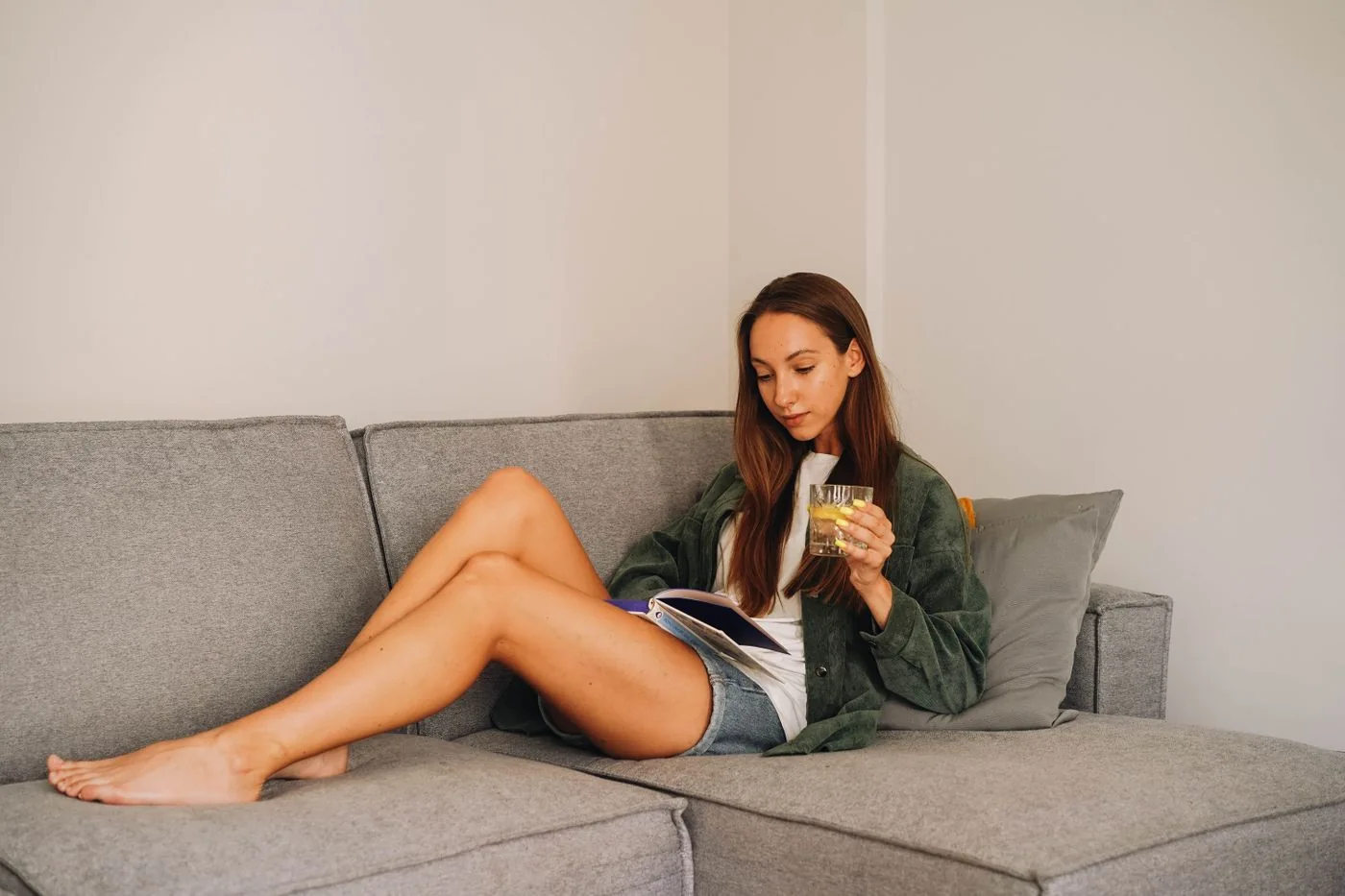 Woman reading a book on a grey sofa